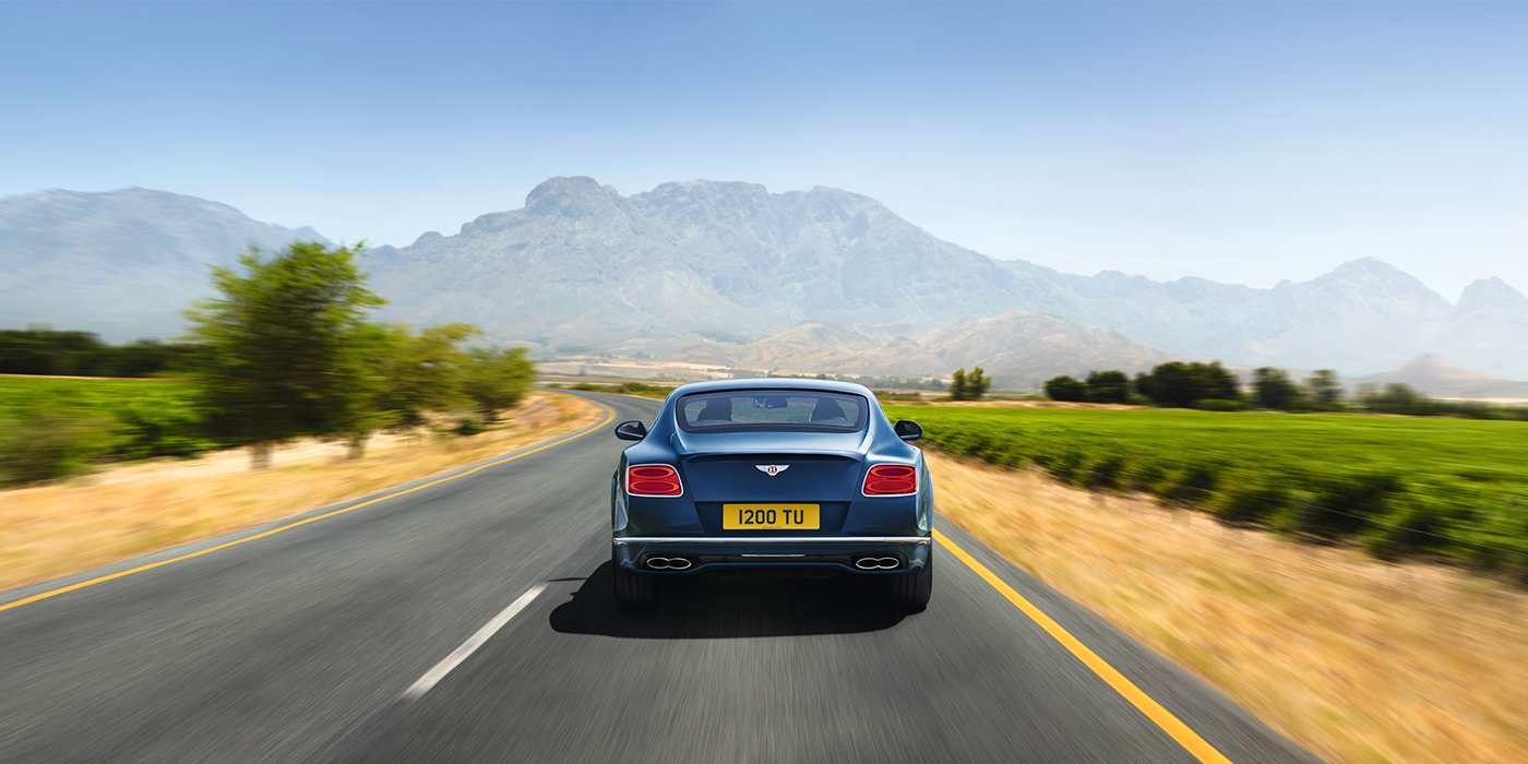 Bentley Zurich Bentley Pre Owned Bentley Continental GT in Marlin blue paint seen from rear on country road