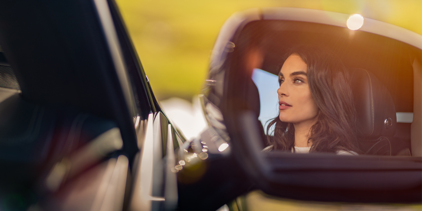 Bentley Zurich profile of dark haired woman's face in mirror of Bentley car in sunlight
