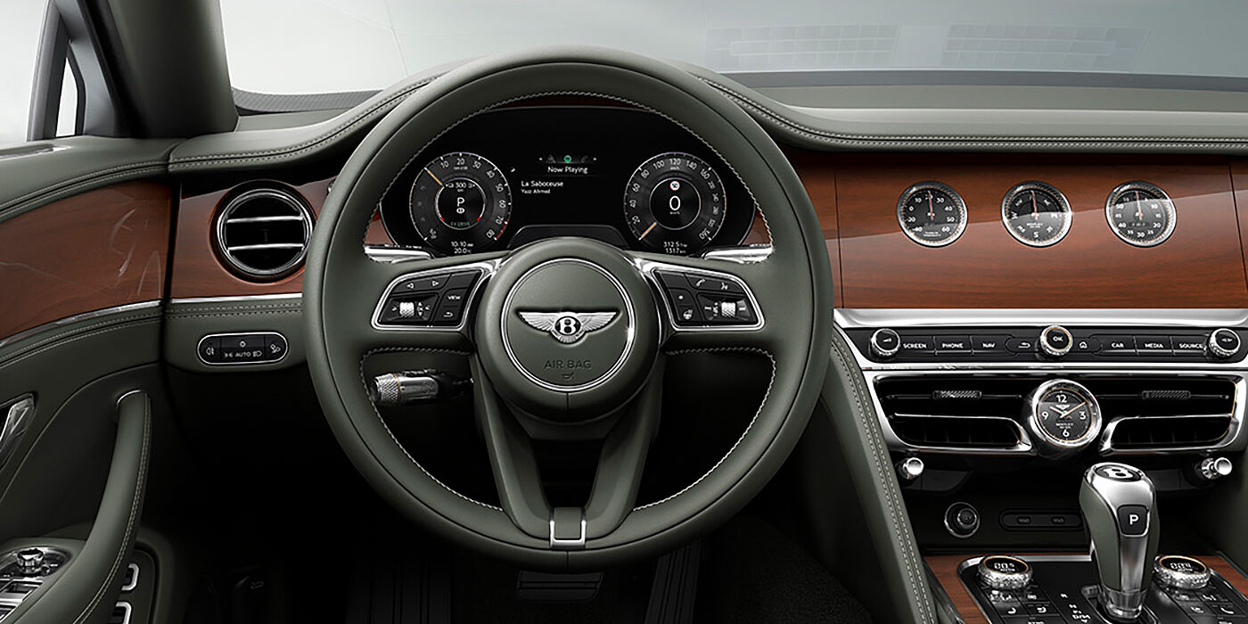 Bentley Zurich New Bentley Flying Spur sedan front cabin in Cumbrian Green hide and Crown Cut walnut veneer showing steering wheel and Rotating Display with three clocks on face