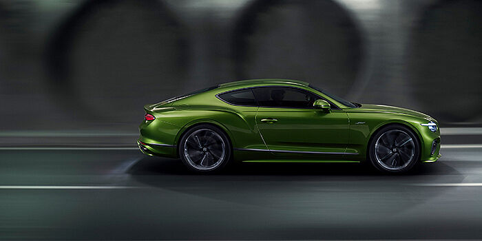  Bentley Zurich Bentley Continental GT coupe in Tourmaline Green paint driving in profile on a dark road