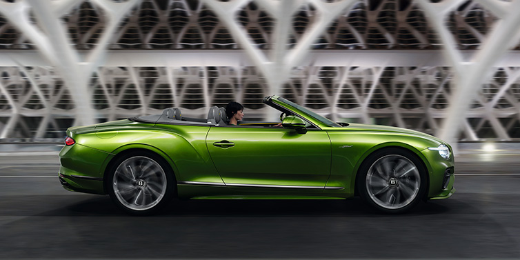 Bentley Zurich Bentley Continental GTC Speed convertible side profile in Tourmaline Green paint driving dynamically on a bridge at night