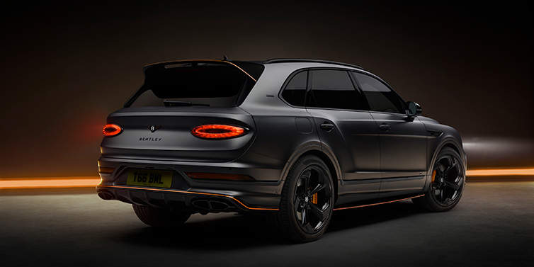 Bentley Zurich Bentley Bentayga S Black Edition SUV rear three quarter in Anthracite Satin paint against a dark red and yellow background