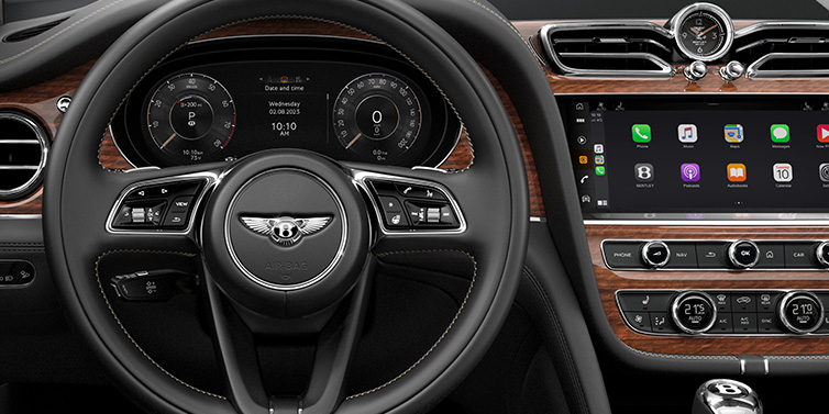 Bentley Zurich Bentley Bentayga SUV front interior detail of steering wheel and driver screens surrounded by Beluga black hide and Crown Cut Walnut veneer